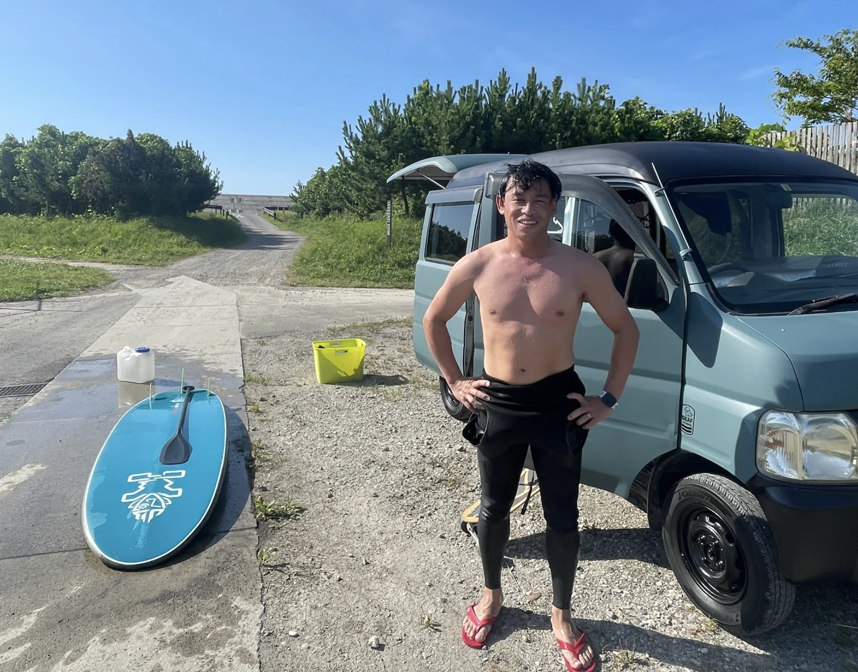 サーフボードと車のそばに立つ岩佐大輝さん