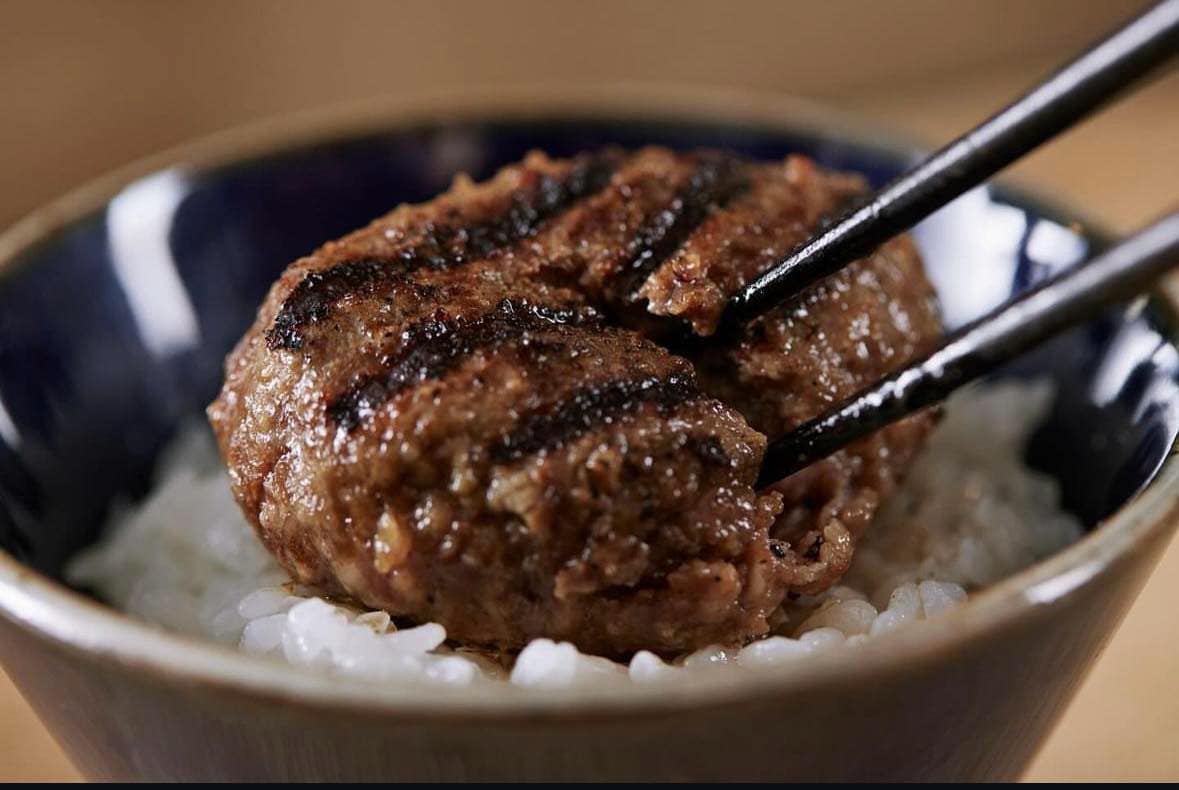 箸で割った炭火焼きハンバーグを炊きたてのご飯とともに味わう様子