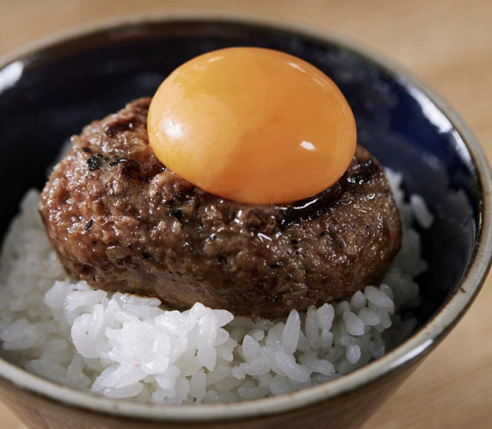 炭火焼きハンバーグと炊きたてのご飯に卵黄を載せた料理