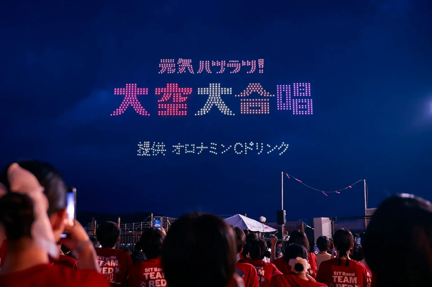 夜空に元気ハツラツと大空大合唱の文字を描いたオロナミンCのドローンショー